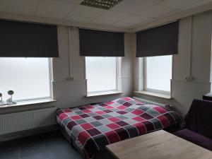 um quarto com uma cama xadrez e janelas em Casa Lommel em Lommel