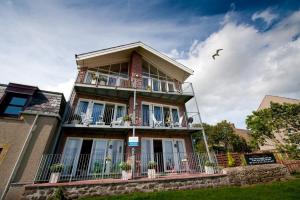a house with a balcony and a bird flying in the sky at Bayview Bed and Breakfast in Stonehaven
