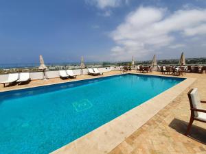 einen Pool mit Stühlen und Tischen auf einem Gebäude in der Unterkunft Hotel Rabat - A member of Barceló Hotel Group in Rabat