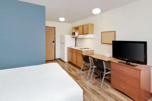 a hotel room with a bed and a desk with a television at WoodSpring Suites Council Bluffs in Council Bluffs