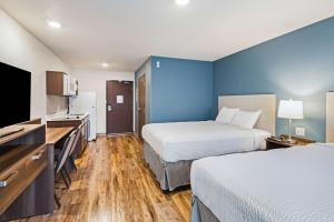 um quarto de hotel com duas camas e uma televisão de ecrã plano em WoodSpring Suites Davenport Quad Cities em Davenport