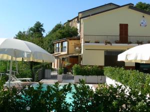 a pool with an umbrella and a house at Agriturismo La Filomena in Montefortino
