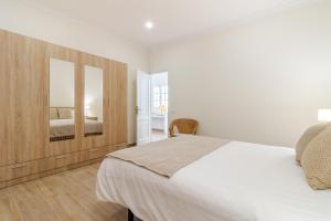 Habitación blanca con cama y espejo en Flatguest Amate, en Las Palmas de Gran Canaria