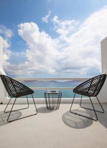 dwa krzesła i stół na balkonie z widokiem na ocean w obiekcie Obsession Mykonos w mieście Agios Stefanos Avliotes