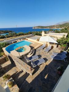 - une piscine avec des chaises longues et un parasol dans l'établissement Villa Azure Sea, Istron, à Istron
