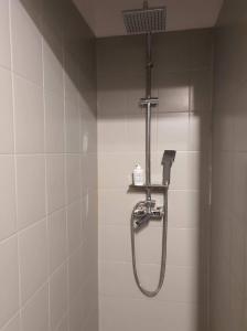 La salle de bains est pourvue d'une douche et de carrelage blanc. dans l'établissement Schodami do Nieba, à Cracovie