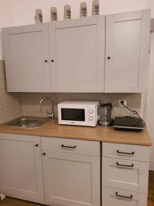 une cuisine avec des placards blancs et un four micro-ondes sur un comptoir dans l'établissement Schodami do Nieba, à Cracovie