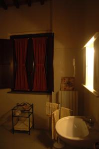 baño con bañera, lavabo y cortinas rojas en Palazzo Bonfranceschi, en Belforte del Chienti