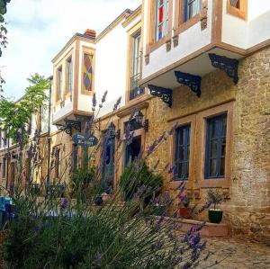 a stone building with windows and flowers in front of it at Ziyabey Konagi in Ayvalık