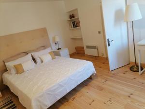 Schlafzimmer mit einem großen weißen Bett und Holzböden in der Unterkunft Chez Laurence 2 pieces 43 m2 à 30 minutes de la mer in Pignans