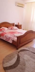 een slaapkamer met een houten bed en een tapijt bij Casa Mihaela in Mangalia