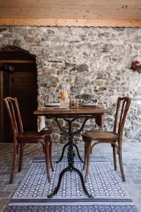 l'Herbier - chambre d'Hôtes - في Marnaz: طاولة خشبية وكرسيين امام جدار حجري