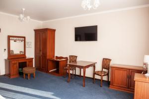 a room with a desk and a table and chairs at AZIMUT Hotel Nalchik in Nalchik