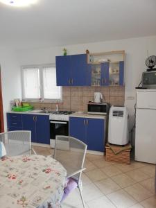 cocina con armarios azules, mesa y sillas en Apartments Defrančeski, en Kavran