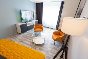 Cette chambre comprend un lit, deux chaises et une télévision. dans l'établissement Bremerhavener Suite 2, à Bremerhaven