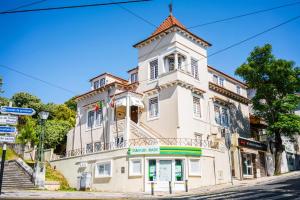 a white building with a tower on a street at Hotel Residencial Alentejana in Coimbra