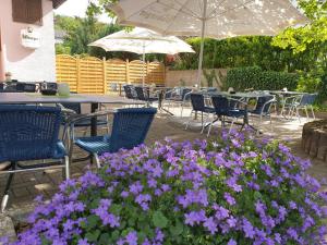 un patio con mesas, sillas y flores púrpuras en HRC Pfeffermühle, en Landstuhl