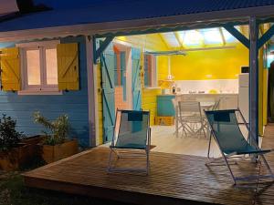 two chairs on a wooden deck with a kitchen at Les Cauris de l'Anse in Sainte-Anne