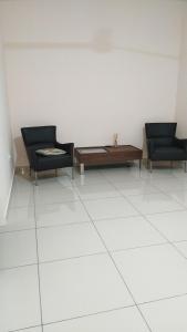 two chairs and a coffee table on a white tile floor at FangFei Homestay in Seremban