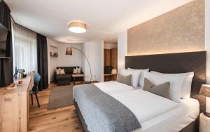 una camera con un grande letto e un soggiorno di Chalet Grumer Suites&Spa a Soprabolzano