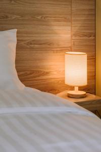 a white bed with a lamp on a night stand at The Cape Hotel in Udon Thani