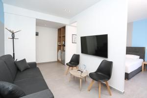 un salon avec un canapé, des chaises et une télévision dans l'établissement Downtown Seaside Suites, à Thessalonique