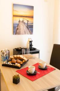 una mesa con una bandeja de bollería y dos tazas en DIMORA ROSSA, en Sottomarina
