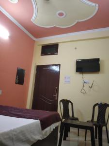 a bedroom with two chairs and a bed and a tv at HOTEL AWADH KAILASH in Bahraich