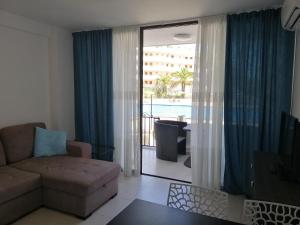 a living room with a couch and a view of the pool at Сozy apartment in Las Americas in Playa Fañabe
