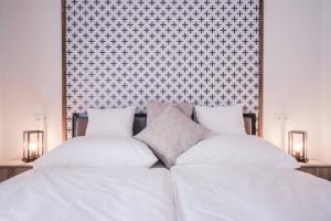 a bed with white sheets and two pillows at Mathias Rex in Szentendre