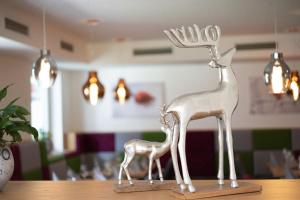 une statue métallique d'un cerf et d'une petite girafe sur une table dans l'établissement Wanderhotel Erika, à Wagrain