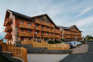 a large wooden building with cars parked in front of it at apartmán Ela - TATRY GOLF in Veľká Lomnica