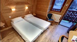 a small room with a bed and a chair at Hotel Les Chalets in Brides-les-Bains