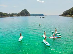 a group of people on surfboards in the water at Guesthouse All you need in Shimoda