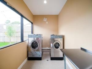 two washing machines in a laundry room with a window at OYO Hotel Houston N Fm-1960 Champions TX in Houston