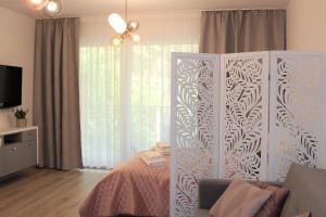 a bedroom with a bed and a tv and curtains at Apartament Mariva B106 z balkonem - Pobierowo - przy samym morzu - obiekt Euronia in Pobierowo