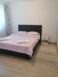 1 dormitorio con cama con marco negro y sábanas rosas en AmigoHD², en Hunedoara