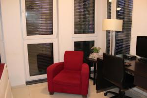 einen roten Stuhl und einen Schreibtisch in einem Zimmer mit Fenstern in der Unterkunft Lovely Studio Cologne West - Neues Momomotel in Köln