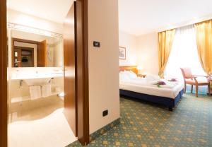 Habitación de hotel con cama y baño en Hotel Eden, en Levico Terme