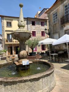 a fountain in a courtyard with tables and umbrellas at Casa da Ana Boutique Guest House in Barcelos