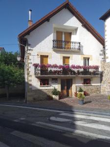 a white building with flowers on balconies on a street at Casa rural Lucuj in Jaurrieta