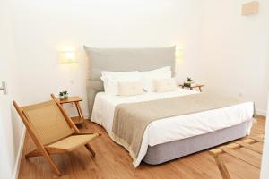 a bedroom with a large bed and a chair at Casas da Chaminé Eco Country Lodge in Nordeste