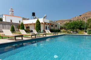 a swimming pool with chairs and a house at Agarathos Traditional Rooms with Pool in Kissamos
