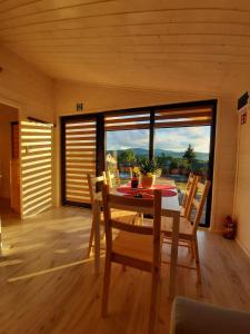 a dining room with a table and chairs and a large window at Kantadaj Village Domki Prestige in Prudnik