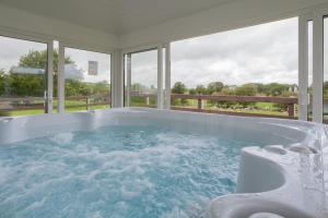 a large bath tub in a room with windows at Beautiful mountain views & private hot tub in Kilcoo