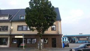 um edifício com uma árvore em frente em Monteurwohnungen Lerch Santos em Mönchengladbach