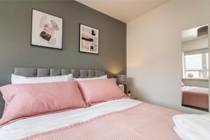 Blackstone Walk - Fabulous Houses with Parking في نوتينغهام: غرفة نوم بسرير وردي مع صورتين على الحائط