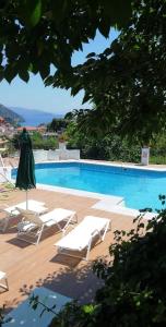 a pool with lounge chairs and a umbrella and a pool at Magda's Hotel Apartments in Parga