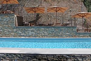 a swimming pool with umbrellas on a stone wall at Boutique Hotel NOAE by Emerald Stay in Oletta