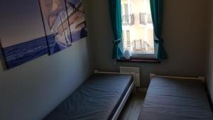 a small room with two beds and a window at Apartament Krynica Morska Rybacka Nad Zalewem in Krynica Morska